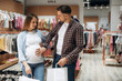 © standret - Finished shopping, holding bags. Pregnant woman with man are in the kid's clothing store