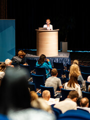 Wall Mural - female speaker giving a talk on corporate business conference. unrecognizable people in audience at 