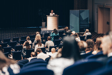 Wall Mural - female speaker giving a talk on corporate business conference. unrecognizable people in audience at 