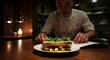 © DEGE - Chef folding menu next to plated bone marrow with gremolata, candlelight reflecting off the slick roasted bone