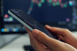 © sementsova321 - A person's hands cradle a smartphone displaying a stock market analysis chart with red and green indicators, set against a softly blurred backdrop.