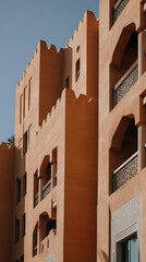 Aufkleber - Warm-toned architectural facade featuring decorative balconies, crenellated edges, and Moorish-inspired designs against a clear blue sky, bathed in sunlight.