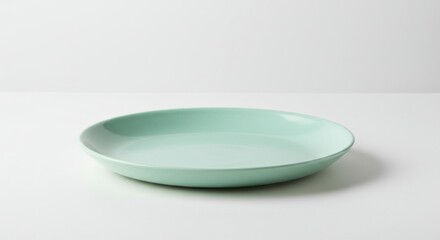 Poster - A simple light green plate sits on a white surface in a well lit studio environment setting today