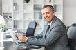 © Pixel-Shot - Portrait of handsome mature businessman working with laptop at table in office