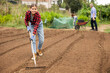 © JackF - Girl working in vegetable garden, raking soil on patch while preparing for planting seedlings