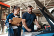 © peopleimages.com - People, car mechanic and clipboard in garage for inspection with teamwork, collaboration and maintenance. Partner, employee and vehicle repairs or service as engineer with small business and workshop