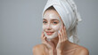 © Cathy - Portrait of smiling young woman n towel removing cosmetic mask from face. Isolated over grey studio background.