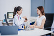 © NanSan - An Asian woman sits at a table consulting with a female doctor. They discuss her symptoms related to stress and depression. The doctor listens attentively and recommends treatment and medication