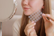 © st.kolesnikov - Closeup of girl applying acne patch for skincare, showing hydrocolloid spot treatment for pimples.