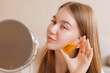 © st.kolesnikov - Girl with glowing skin showing yellow facial oil near face, beauty and skincare concept.