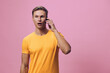 © SHOTPRIME STUDIO - surprised man talking phone chat with AI digital communication smartphone against pink background casual yellow t-shirt young caucasian