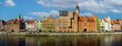 © Kotangens - Panoramic view of colorful historic buildings along the Motlawa River in Gdansk, Poland. Features vibrant architecture with a backdrop of blue sky and scattered clouds