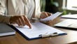 © Mdragon - Close-up of a person's hands and documents discussing a contract with a business partner