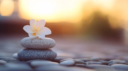 Leinwandbilder - Serene sunset scene featuring a delicate white plumeria flower atop a balanced stack of grey stones, symbolizing peace and tranquility. : Generative AI
