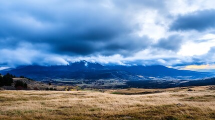 Aufkleber - Dramatic blue sky over a vast mountain range and golden autumnal field, showcasing a serene landscape with hints of a distant village. : Generative AI