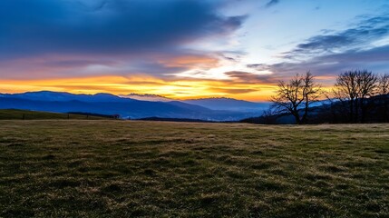 Poster - Serene sunset over a vast grassy field, silhouetted trees, and majestic mountain range in the distance, showcasing vibrant orange and blue hues in the sky. : Generative AI