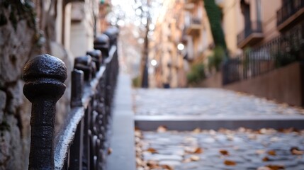 Poster - Close-up view of an ornate, dark metal fence post, with a blurred background showing a cobblestone street and old European-style buildings on a fall day. : Generative AI