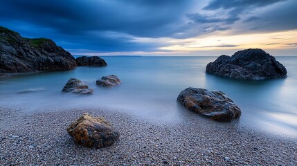 Poster - Serene coastal scene at twilight: smooth water laps gently against a pebble beach, dark rocks jutting from the calm sea under a dramatic sky. : Generative AI
