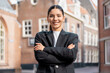 © Andrei - Attractive young woman realtor in sleek black suit stands confidently on city street, ideal for real estate branding, urban professionalism, career empowerment, or modern leadership
