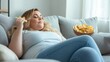 © olga_demina - Person is comfortably lounging on a sofa, savoring chips from a bowl. The setting is cozy and relaxed, emphasizing leisure and enjoyment during a quiet moment at home