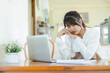 © Sumala - Asian woman digital nomad remote working tired resting at home office with laptop and documents