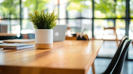 Aufkleber - A small potted plant sits on a light wood table in a modern office space, near blurred laptops and chairs, bathed in natural light from large windows. : Generative AI