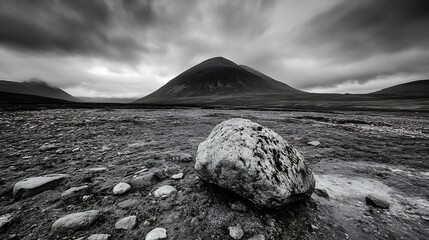 Poster - Dramatic monochrome landscape featuring a large boulder in the foreground, with imposing, dark mountains under a stormy sky, conveying a sense of solitude and vastness. : Generative AI