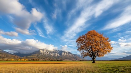 Poster - Solitary autumn tree in vibrant golden foliage stands majestically against a backdrop of majestic mountains under a dramatic sky with flowing clouds. : Generative AI