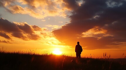 Poster - Silhouette of a man standing in tall grass, watching a vibrant sunset with fiery orange and dark clouds in the sky.  The sun is setting behind him, casting a warm golden glow. : Generative AI
