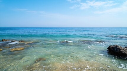 Poster - Serene coastal scene featuring clear turquoise water gently lapping against sunlit rocks under a vibrant blue sky with a few wispy clouds. : Generative AI