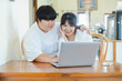 © Sumala - Asian couple using laptop together at home enjoying activity and lifestyle with love and support