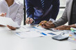 © Wasan - Business people analyzing financial documents around table. Business professionals collaborate, analyze financial data, and plan investments in office.