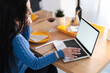 © Studio Marmellata - Woman works on her laptop at home. She is wearing a blue sweater and has a glass of wine nearby.