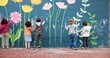 © peopleimages.com - Wall, children and writing with chalk for education, cognitive development and creativity in school. Back, students and kids with learning for drawing mural, inspiration and outdoor in kindergarten