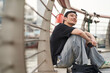 handsome young Asian man sitting beside his bike at waterfront smiling