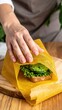© WutStock02 - A person carefully adds fresh vegetables, grilled chicken, and sauces into a large tortilla wrap, preparing a delicious and colorful meal.