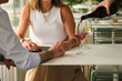 © Ladanifer - Senior couple holding hands and using tablet while waiter pours red wine at restaurant table