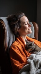 Poster - A woman sits in an armchair, wrapped in an orange robe, peacefully relaxing with a cat resting against her. The dim lighting creates a serene atmosphere, perfect for unwinding