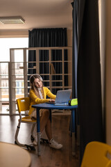 Aufkleber - Engaged schoolgirl in headphones smiling during online STEM learning in cozy educational space. Girl explores STEM education and digital skills development during interactive online learning