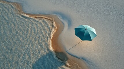 Aufkleber - A beach umbrella stands alone on soft sand, casting its shadow onto the shore as calm waves lap gently at the edge. The sun illuminates the scene, inviting relaxation