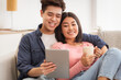 © Prostock-studio - Asian Boyfriend And Girlfriend Using Tablet Computer Watching Movie Online Embracing Sitting On Sofa At Home Relaxing On Weekend Morning. Modern Gadgets, Chinese Family Lifestyle
