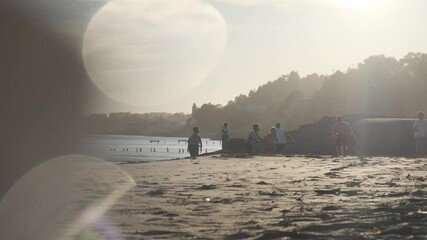 Wall Mural - silhouetted group enjoying golden sunset moments on sandy portuguese coastline, backlit friends play