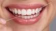 © Chandlerlikes - Oral care routine, woman smiling while using floss, close-up image with soft grey background.
