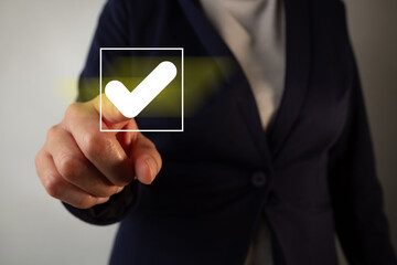 Poster - a businesswoman pointing to a checkmark in a square with a bright yellow light