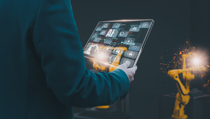 Wall Mural - industry engineer in smart factory using transparent glass tablet to control automated robotic arm w