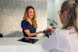 © DusanJelicic - Smiling nurse accepting contactless payment from a patient at the reception desk of a modern medical clinic, highlighting convenient and efficient healthcare transactions