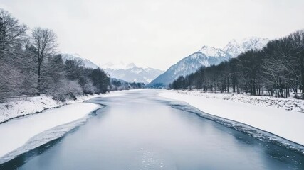 Poster - Partially frozen river meandering through a snowy valley, surrounded by snow covered trees and majestic mountains, creating a serene winter landscape filled with natural beauty