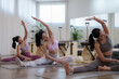 © Phimwilai - Three asian women are sitting on yoga mats, performing stretching exercises in a pilates studio, demonstrating flexibility and promoting healthy lifestyle choices