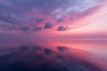 Poster - Pink and purple clouds reflect on calm water at sunset, creating tranquil and dreamy seascape with soft light and peaceful atmosphere
