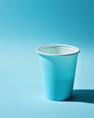 Poster - Minimalist studio shot of a light blue paper cup on a matching background casting a shadow, clean design, product photography